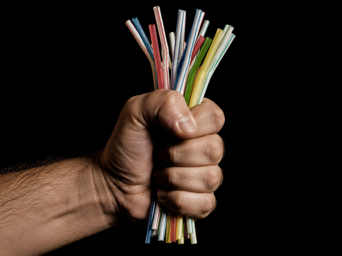 A hand clutching straws. Photo Credit: Kawika Rogers