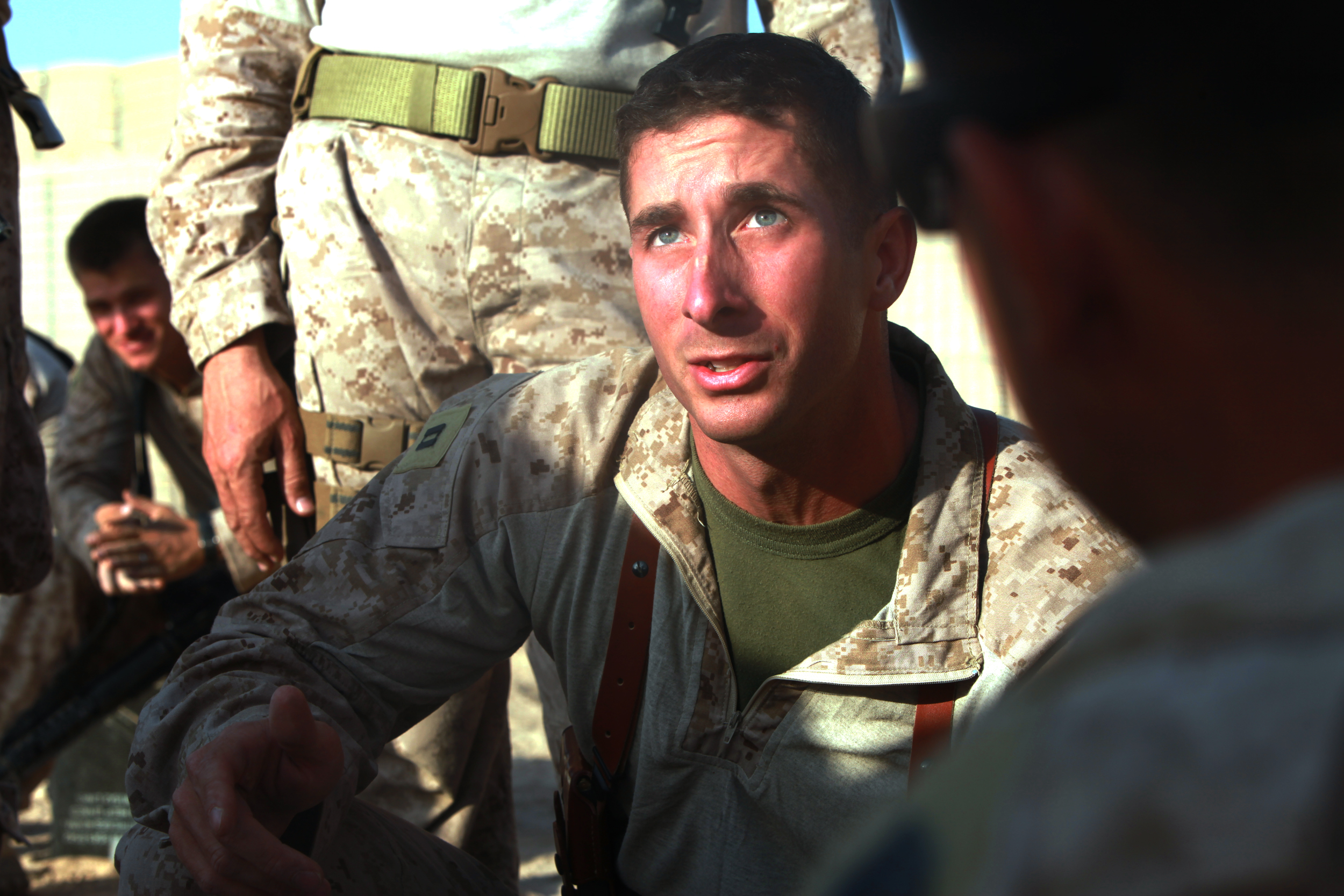 A Marine captain crouches at eye level with his Marines and talks them through the next day's mission in Afghanistan